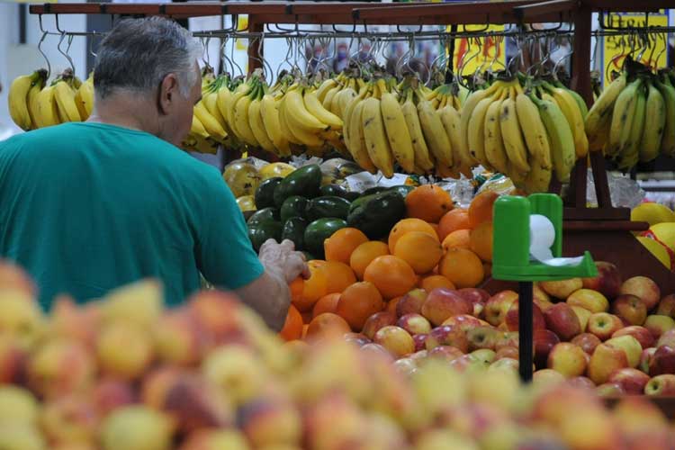 Homem de camiseta verde compra frutas em supermercado